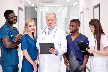 Skillful general student practitioners discussing human health with senior doctor, having conversation with experienced professional medical worker, in hospital