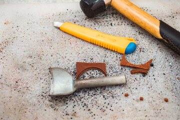 A chisel, a hammer and a stationery knife lie on the table next to stumps of skin