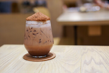 Iced Chocolate Bomb topped with cocoa powder likes volcano on wooden table in cafe.