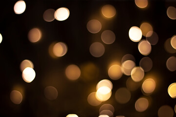 Bokeh. Small gold defocused lights on a dark brown background. Design concept
