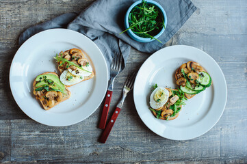 various morning vegetarian toast set with mushrooms, avocado, arugula, cucumber, micro green and eggs. Healthy food on rustic wooden background