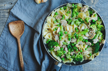 pan with cooked tasty italian vegetarian pasta with broccoli, green beans, mushrooms in creamy sauce. Tasty lunch or dinner