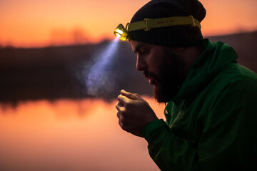 Hiker with headlamp warming up hands in evening © kegfire