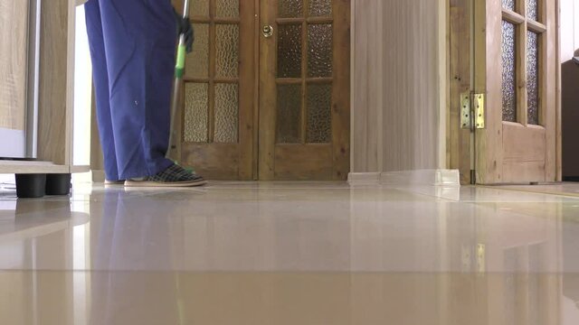 Wet cleaning of the floor in an apartment or office with a mop. The male worker is engaged in slaughter in the apartment.