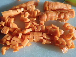 cutting raw carrot on a white cutting board