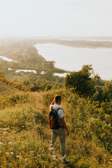 a man stands in the grass on a hillside in the rays of the setting sun