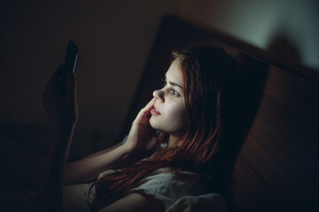 woman lies in bed before going to bed with phone in hands communication lifestyle leisure
