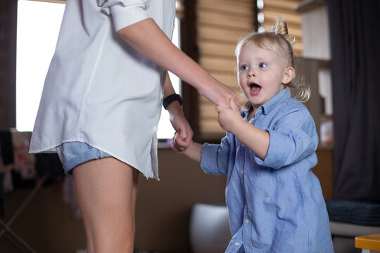 Mom And Daughter Are Dancing At Home Holding Hands.