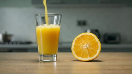 Filling glass with orange juice in the kitchen. Close up 