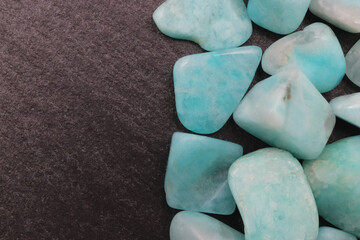 Amazonite jewel heap on black stone half background. Pile mineral pebbles texture. Place for text.