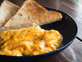 焼いたソーセージとトースト、とろとろのオムレツのクローズアップ。