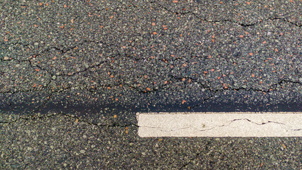 Asphalt road with white marking line, texture with cracks 