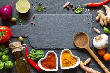Cooking background. Vegetables, herbs and spices on black slate