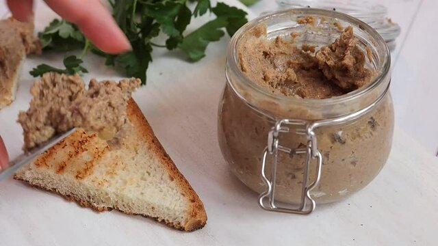 Woman smear chicken pate on toast, making sandwiches for breakfast.