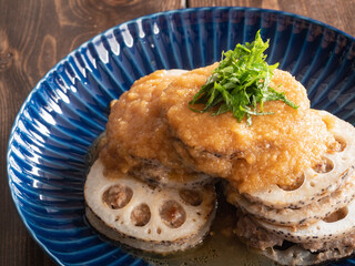 蓮根料理。蓮根でミンチ肉を挟んでこんがり焼いた料理に大葉とソースをトッピング。