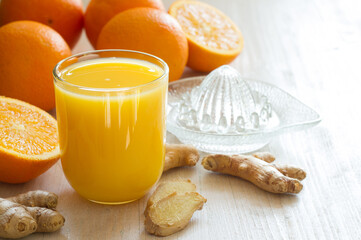 Healthy and fresh orange juice with addition of ginger on white wooden table