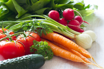 Assortment of fresh spring vegetables on white wooden background