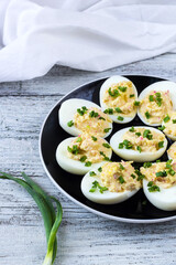 stuffed eggs with crab sticks, mayonnaise and green onion on black plate