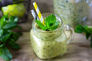 Homemade green smoothie in a jar with spinach, apple, kiwi and mint in glass jar and ingredients. Detox, diet, healthy, vegetarian food concept.