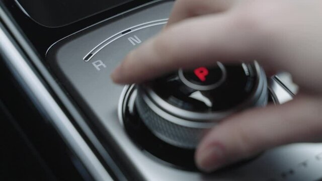 The man hand in close-up switches the transmission of an automatic gearbox. Parking, drive, reverse. Close-up of the male driver hand switches the automatic transmission lever from parking to drive