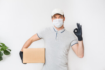 Fototapeta na wymiar Courier in medical rubber gloves and protective mask holding cardboard boxes. Delivery service. Quarantine.