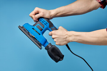 Electric sanding machine for home handyman use, on blue background copy spacefor advertisement.