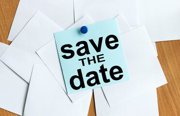 save the date. text on blue sticker on table button holds sticker