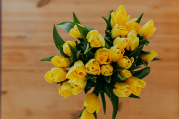 Bright fresh yellow tulips on wooden background. Spring flowers on wooden table. Bunch of yellow tulips on wooden table.