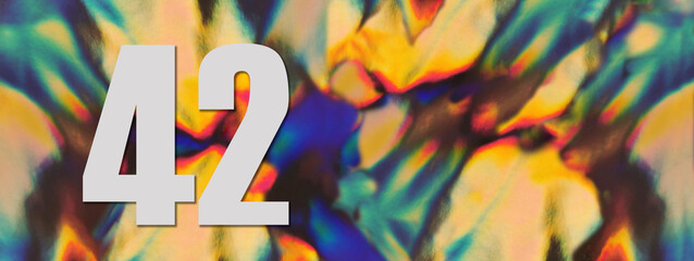 Wide banner. Number 42 forty two on the blurry iridescent holographic foil background. Colorful reflective folia. Greeting card. Copy space. Flat lay.