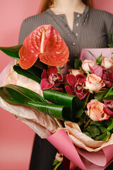 The girl holds a pink delicate bouquet with anthurium and roses.