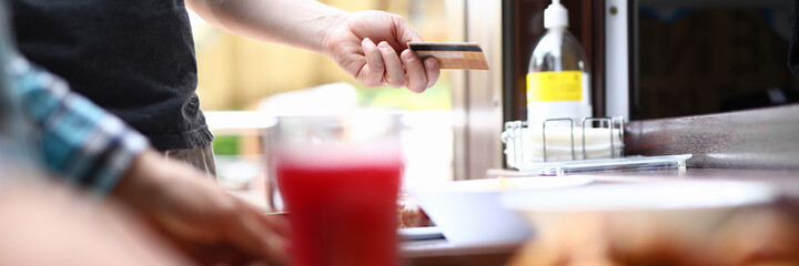 Man's hand holds bank plastic card on the background of food. Payment by credit bank cards in public places concept