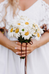 wedding bouquet of daisies in the hands of the bride