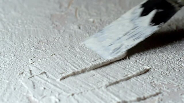 application of white granular decorative plaster on plywood, spatula close-up