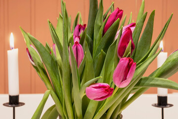 A beautiful romantic bouquet of purple tulips against a backdrop of burning wax candles.
