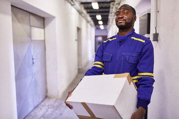 Afrikanischer Arbeiter als Aushilfe trägt Karton