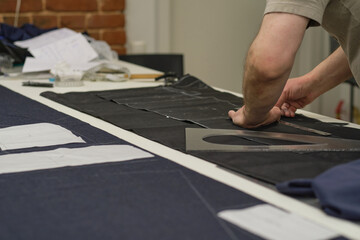 Dressmaker cutting dress fabric on sketch line. Fashion designer tailor or sewer in workshop studio designing new collection clothes. Business owner shop and entrepreneur concept