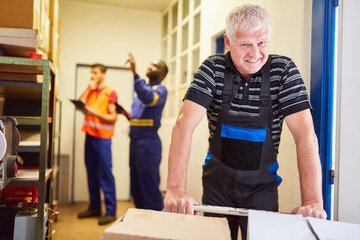 Obraz na płótnie Canvas Lächelnder Arbeiter im Warenlager mit Paketen