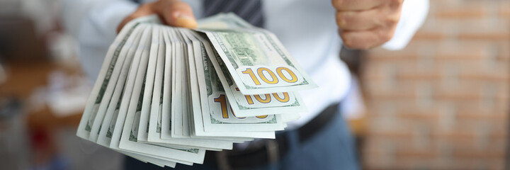 Businessman holds one hundred dollar bills in his hand. High earnings on the internet concept