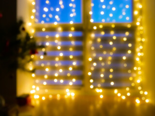 Beautiful blurred flickering yellow light. Home decoration with garlands on the window, night Bokeh...