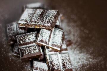 Dark chocolate in powdered sugar. Chunks of dark chocolate.
