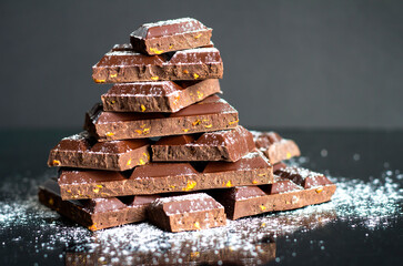 Dark chocolate in powdered sugar. Chunks of dark chocolate.