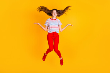 Fototapeta na wymiar Photo of cheerful lady jump throw hair wear striped shirt red pants shoes isolated yellow color background