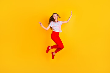 Photo of cute adorable lady jump have fun wear striped shirt red trousers footwear isolated yellow color background