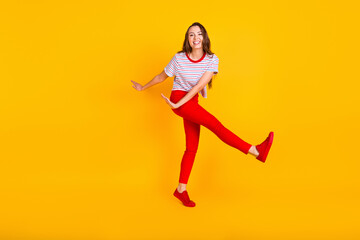 Fototapeta na wymiar Photo of carefree lady dance have fun wear striped shirt red trousers sneakers isolated yellow color background
