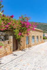 Traditional alley  of Mani region with a narrow street, stone built houses and a blooming bougainvillea in   Limeni village, South Peloponnese , Greece.