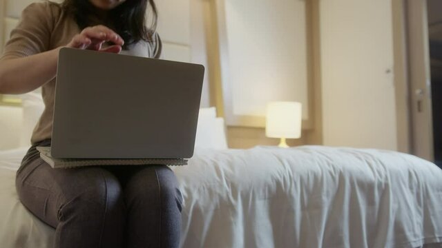 close up asian female wearing casual cloth hand close monitor laptop screen and standing up ready to go out with background of bed hotel room interior