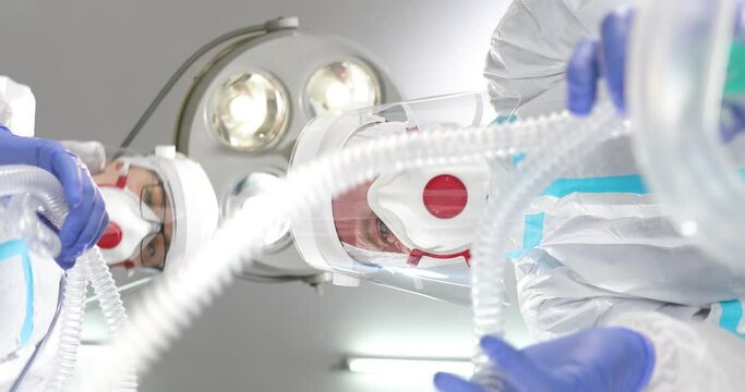 Hospital Coronavirus Emergency Department Ward: Team of Doctors wearing Coveralls, Face Masks doing Medics Saving Lives doing cardiopulmonary resuscitationon . Resuscitation department in a hospital