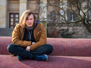 Sad young man sitting alone listen music and try to relax