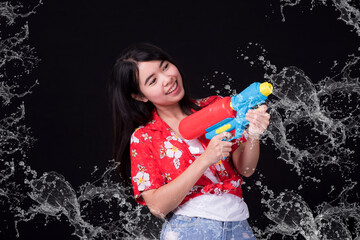 Young happy beauty Asian woman holding plastic water gun at Songkran festival, Thailand. Thai New Year's Day. Isolated on black background.