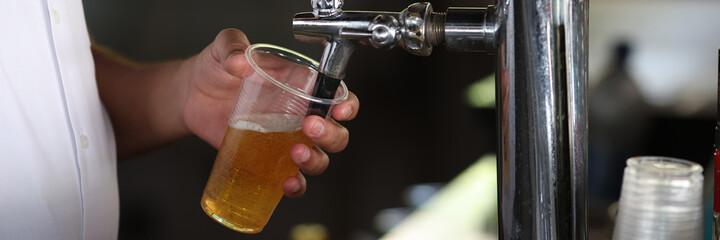 Bartender pours light glass into glass at bar. Beer dispenser concept